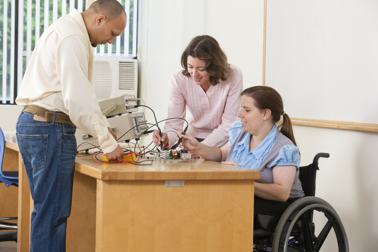 Photo of woman in wheelchair using oscilloscope probes and function generator.